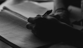 a person holding a pen and writing on a book