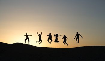 six silhouette of people jumping during sunrise
