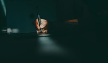 a person writing on a piece of paper with a pen