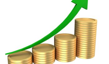 Stacks of coins with an upward trending green arrow