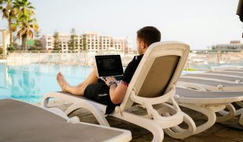 man on sun lounger using laptop