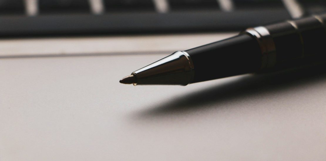 a pen sitting on top of a paper next to a keyboard making a will