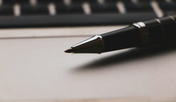 a pen sitting on top of a paper next to a keyboard making a will