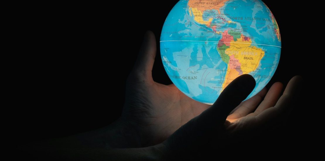 Hand reaching for an illuminated globe, symbolising cross-border wealth planning for UK expats