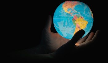 Hand reaching for an illuminated globe, symbolising cross-border wealth planning for UK expats