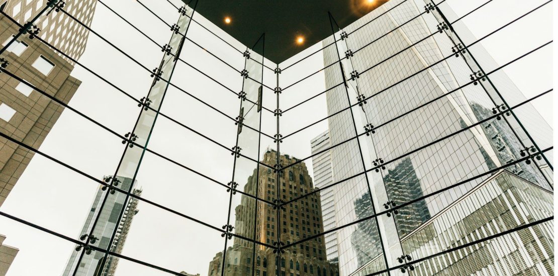 Glass atrium roof framing financial district towers, representing alternative income investments expats hold across multiple jurisdictions