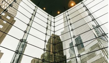 Glass atrium roof framing financial district towers, representing alternative income investments expats hold across multiple jurisdictions