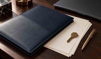 Power of attorney for expats: navy document folder, blank papers and a brass key on a dark wooden desk
