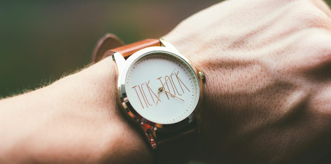 person wearing silver and white analog watch. Sold house listing beside a Will, illustrating how an out-of-date Will can leave inheritance wishes unfulfilled.