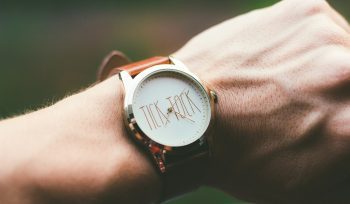 person wearing silver and white analog watch. Sold house listing beside a Will, illustrating how an out-of-date Will can leave inheritance wishes unfulfilled.