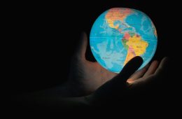 Hand reaching for an illuminated globe, symbolising cross-border wealth planning for UK expats