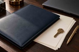 Power of attorney for expats: navy document folder, blank papers and a brass key on a dark wooden desk
