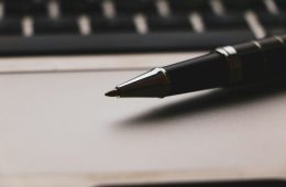 a pen sitting on top of a paper next to a keyboard making a will