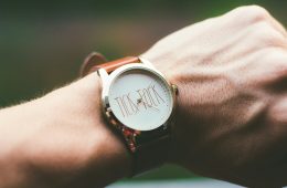 person wearing silver and white analog watch. Sold house listing beside a Will, illustrating how an out-of-date Will can leave inheritance wishes unfulfilled.